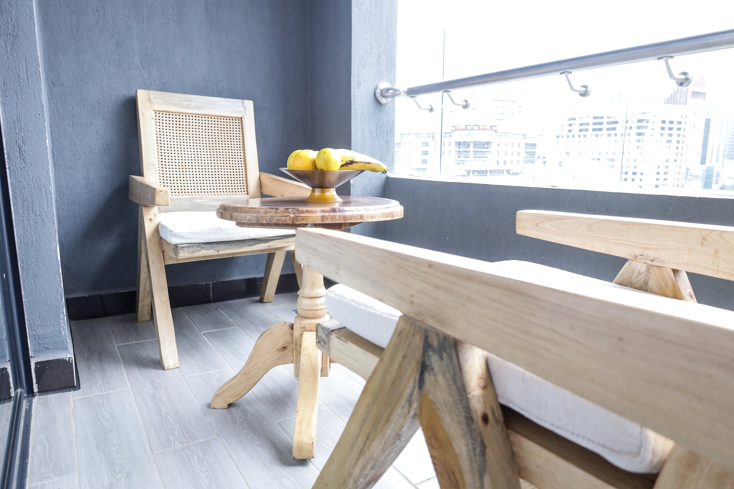 Balcony bench and timber table with a bowl of fruit, looking out over the Nairobi skyline