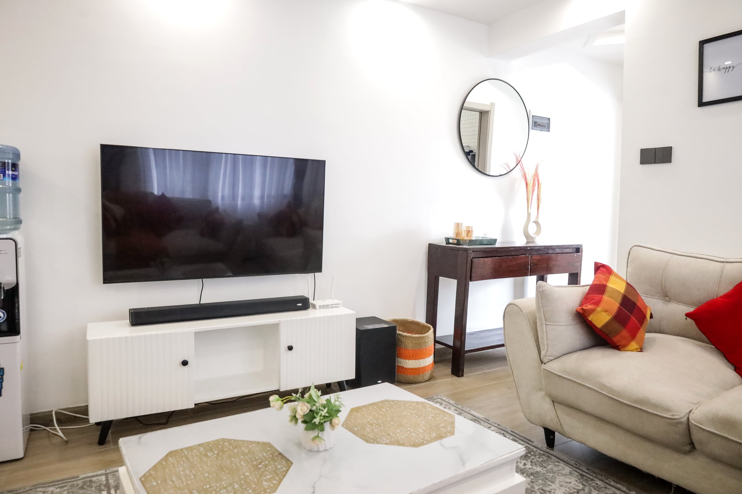Wall-mounted smart TV and soundbar above a low white media unit
